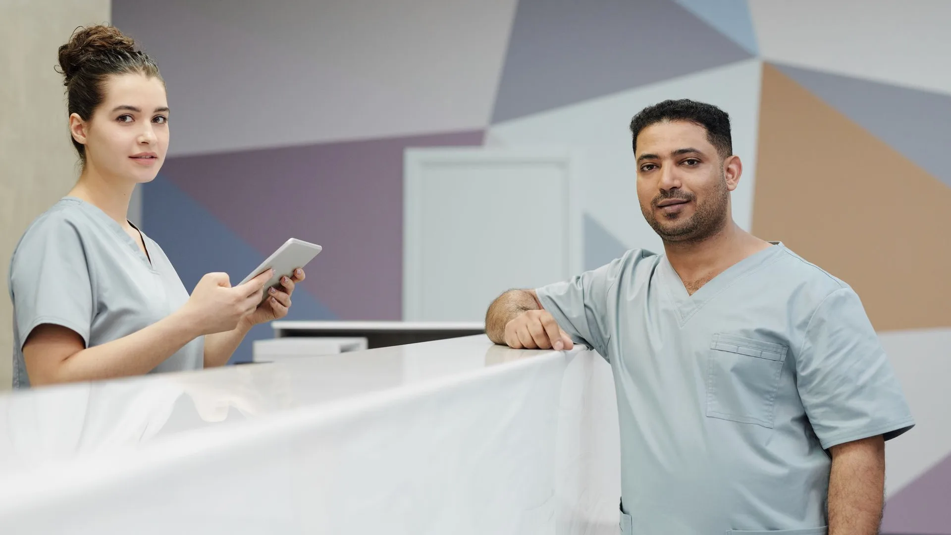 Staff members speaking at the reception desk of a bright outpatient clinic.